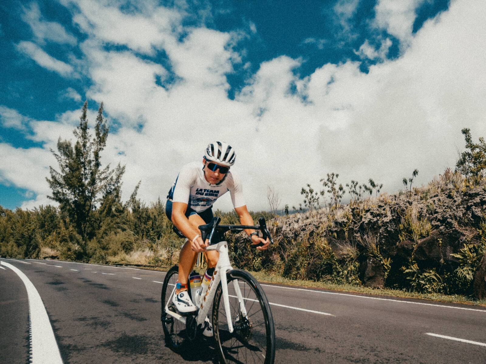 Un cycliste sur la route, ciel bleu et glissière